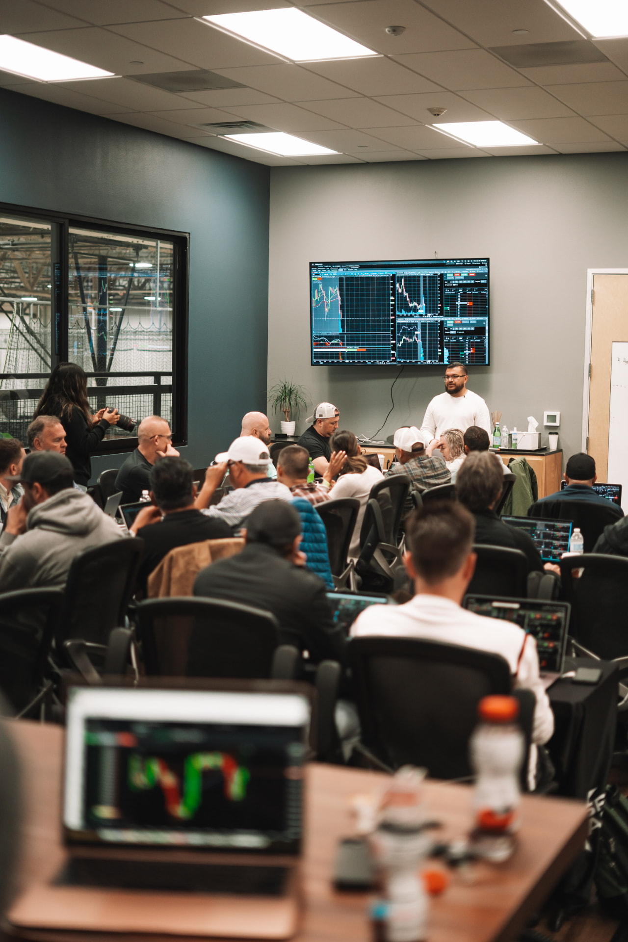 Andrew Diaz addressing a packed bootcamp classroom with a live trading chart on screen