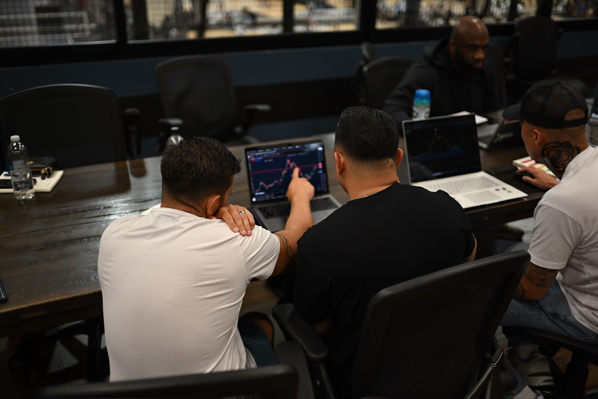 Andrew and other traders huddled around laptops reviewing live charts together